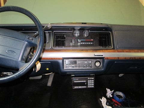 1991 Ford LTD Crown Victoria - The interior of a car shows the dashboard, steering wheel, and center console with aftermarket radio installations.