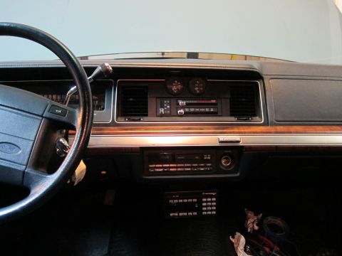 1991 Ford LTD Crown Victoria - The interior of a 1991 Ford Crown Victoria LTD, its dashboard with wood grain accents and a factory radio.
