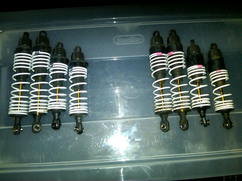 Eight black shock absorbers with white springs and gold shafts, some with pink bands