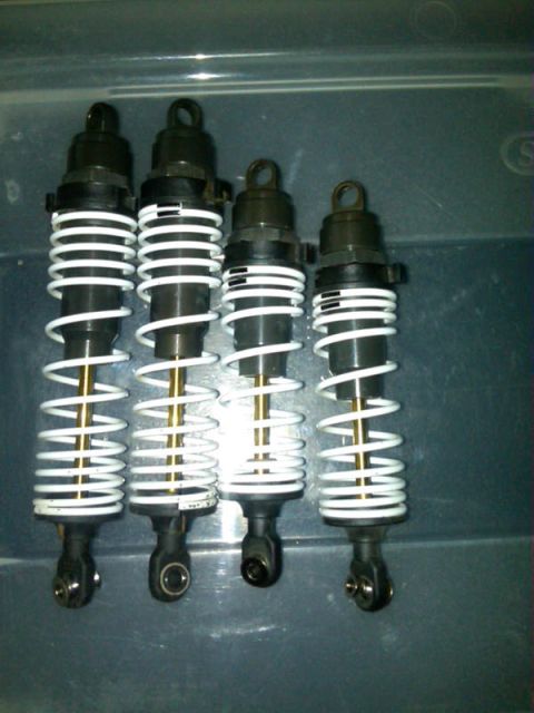 1986 Ford Bronco - A set of four shock absorbers with white coil springs and gold shafts are displayed.