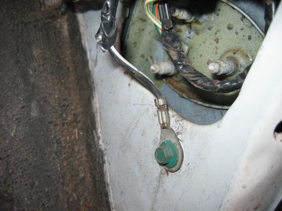 Close-up of a vehicle's wiring ground connection with a green bolt