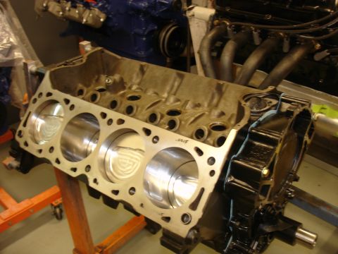 1988 Ford Mustang - Close-up of an engine block with pistons, partially assembled with exhaust manifolds and other engine components.