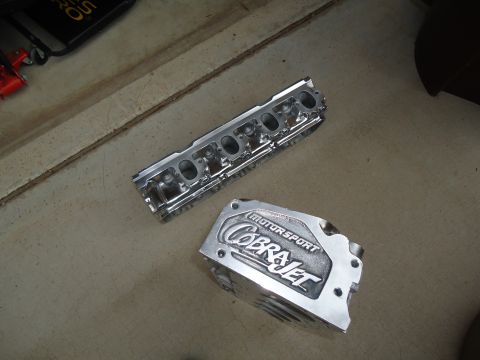 1988 Ford Mustang - Engine parts with 'Cobra Jet' and 'Motorsport' branding are laid out on a concrete surface.