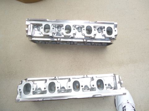 1988 Ford Mustang - Two polished aluminum engine cylinder heads are displayed on a concrete surface, with a watermark at the bottom right.
