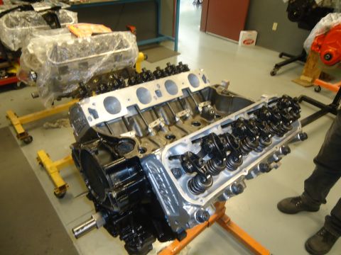 1988 Ford Mustang - An engine is displayed on an orange stand, with another engine covered in plastic behind it.