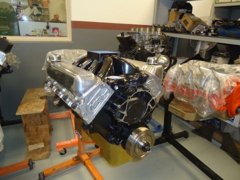 1988 Ford Mustang - A V8 engine with chrome valve covers is displayed on a stand, with another engine partially visible in the background.