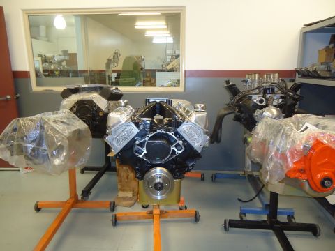 1988 Ford Mustang - Multiple engines are displayed on stands in a workshop setting, with one engine prominent chrome valve covers.