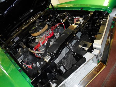 1971 Ford Ranchero - The engine bay of a green 1971 Ford Ranchero is visible, showing the V8 engine and its components.