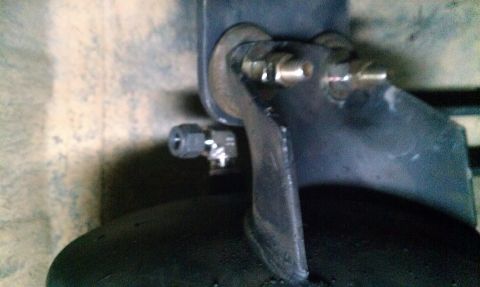 1995 Ford Bronco - A close-up view of a vehicle's suspension component and tire, showing plumbing connections.