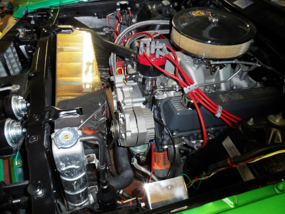 Engine bay with V8 engine, chrome air cleaner, red spark plug wires, and a large radiator