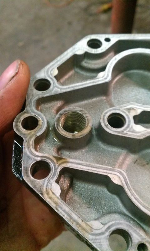 1995 Ford Bronco - A metal engine part is held up for inspection, revealing its internal structure and threaded connection.
