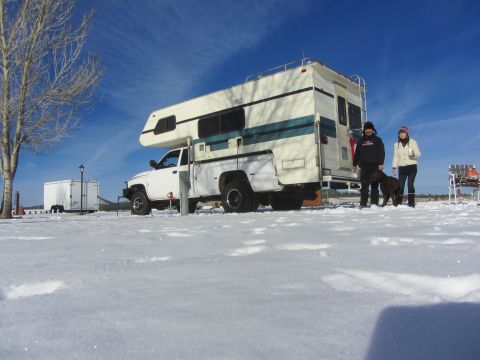 1997 Dodge 3500 - A 1997 Dodge 3500 pickup truck equipped with a camper shell is parked in the snow with two people and a dog nearby.