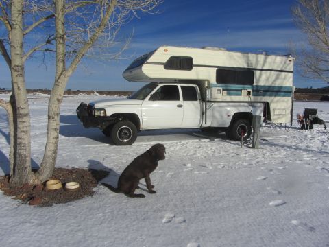 1997 Dodge 3500 - A white 1997 Dodge 3500 pickup truck equipped with a camper shell is parked in a snowy landscape under a clear blue sky.