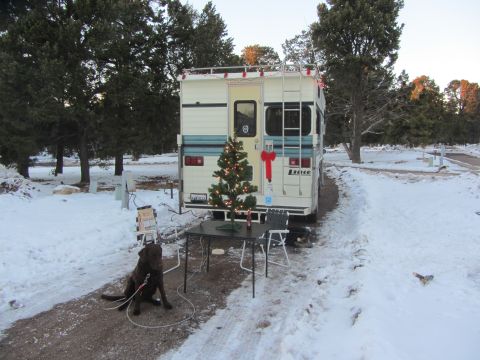 1997 Dodge 3500 - A camper van decorated for Christmas sits in a snowy campsite with a dog.