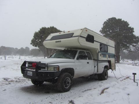 1997 Dodge 3500 - A white 1997 Dodge 3500 pickup truck equipped with a Lance camper shell is parked in a snowy landscape.