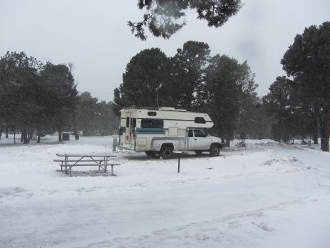 1997 Dodge 3500 - A white 1997 Dodge 3500 pickup truck with a camper shell is parked in a snowy campsite during snowfall.