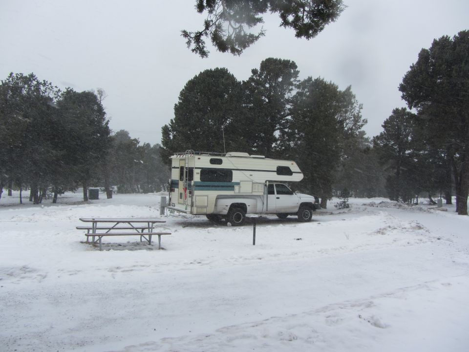 White 1997 Dodge 3500 pickup truck with a camper shell parked in a snowy campsite