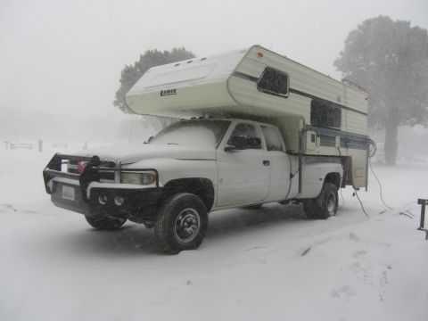 1997 Dodge 3500 - A white 1997 Dodge 3500 pickup truck equipped with a camper shell is seen parked during a heavy snowstorm.