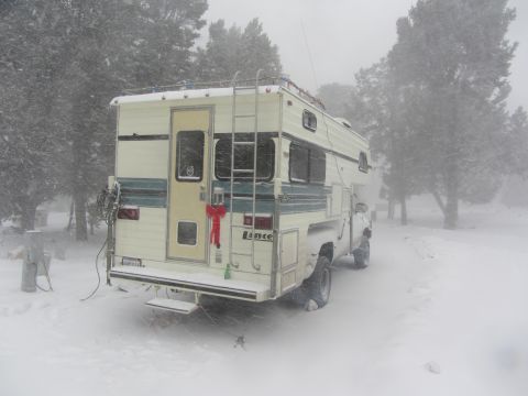 1997 Dodge 3500 - A Lance camper is parked in a snowstorm, decorated with Christmas lights and a red bow.