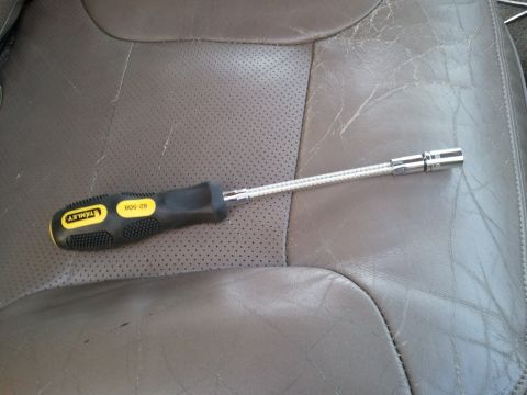 1994 Ford Bronco - Stanley screwdriver with flexible shaft and socket rests on a perforated leather seat.