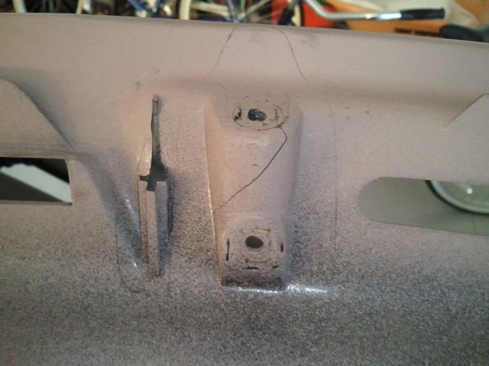 Cracked beige plastic dashboard trim with mounting holes and a cut