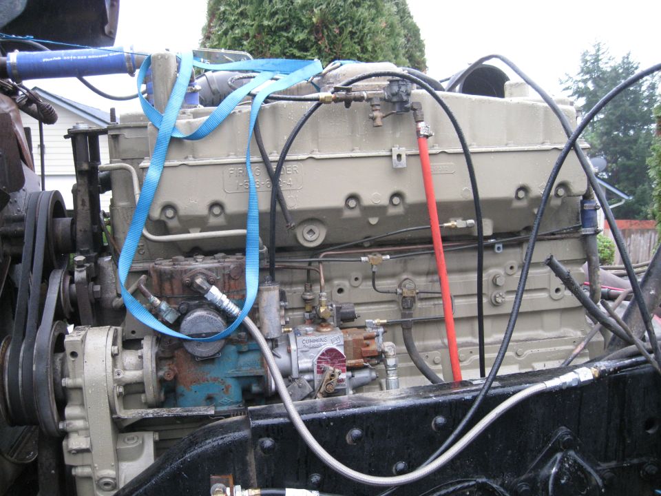 Diesel engine block with fuel lines, hoses, and blue lifting straps. Text on block reads 'FISHER'