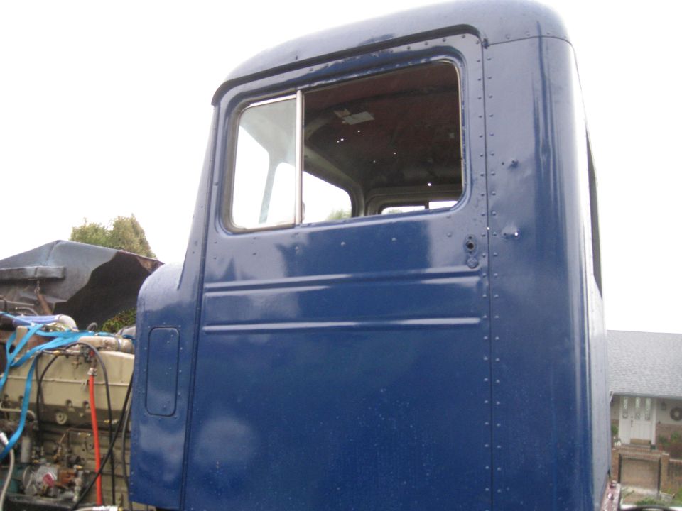 Blue truck cab, side view, with engine visible on the left