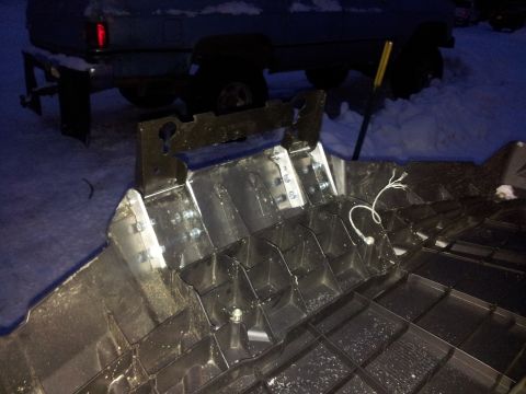1990 Chevrolet Suburban - Damaged vehicle undercarriage part with visible wiring and metal reinforcement.