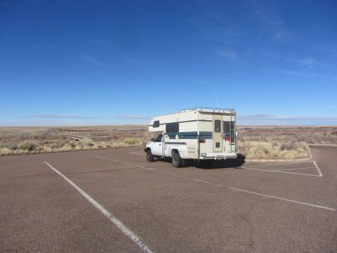 1997 Dodge 3500 - A white pickup truck with a camper shell is parked in a lot under a clear blue sky.