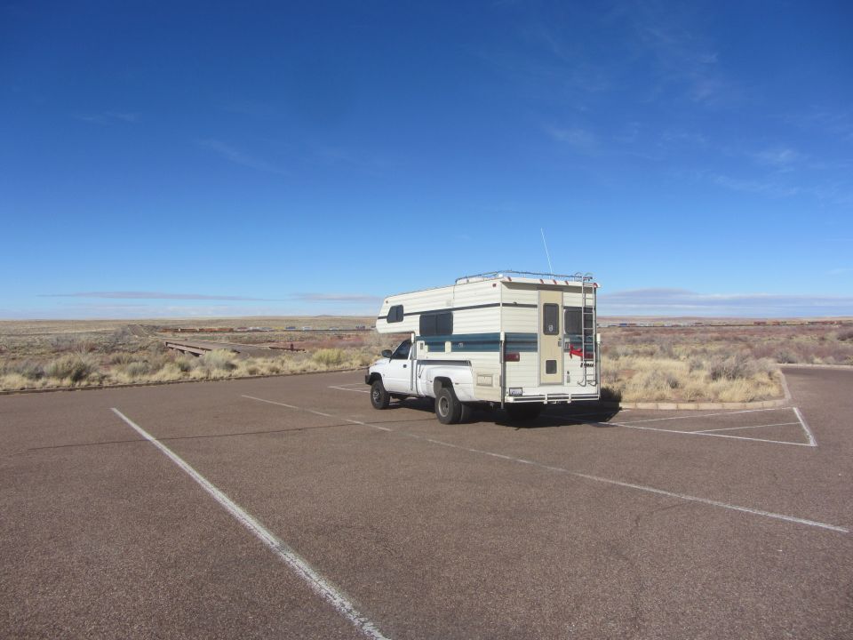 White pickup truck with camper shell parked in a lot, rear view
