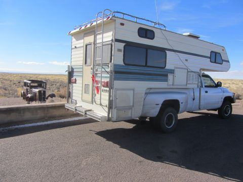1997 Dodge 3500 - A white 1997 Dodge 3500 pickup truck is equipped with a large camper shell, parked outdoors under a clear blue sky.