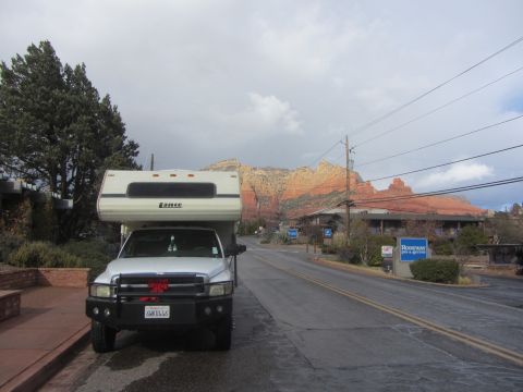 1997 Dodge 3500 - A white pickup truck with a Lance camper shell is parked on the side of the road with red rock formations in the background.