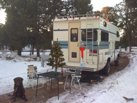 1997 Dodge 3500 - A Lance camper is parked in a snowy area, decorated for Christmas with lights and a tree.