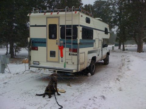 1997 Dodge 3500 - A Lance camper is parked in a snowy landscape with a dog waiting nearby.