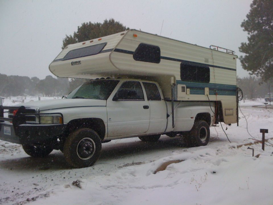 White 1997 Dodge 3500 pickup truck with camper shell in snow