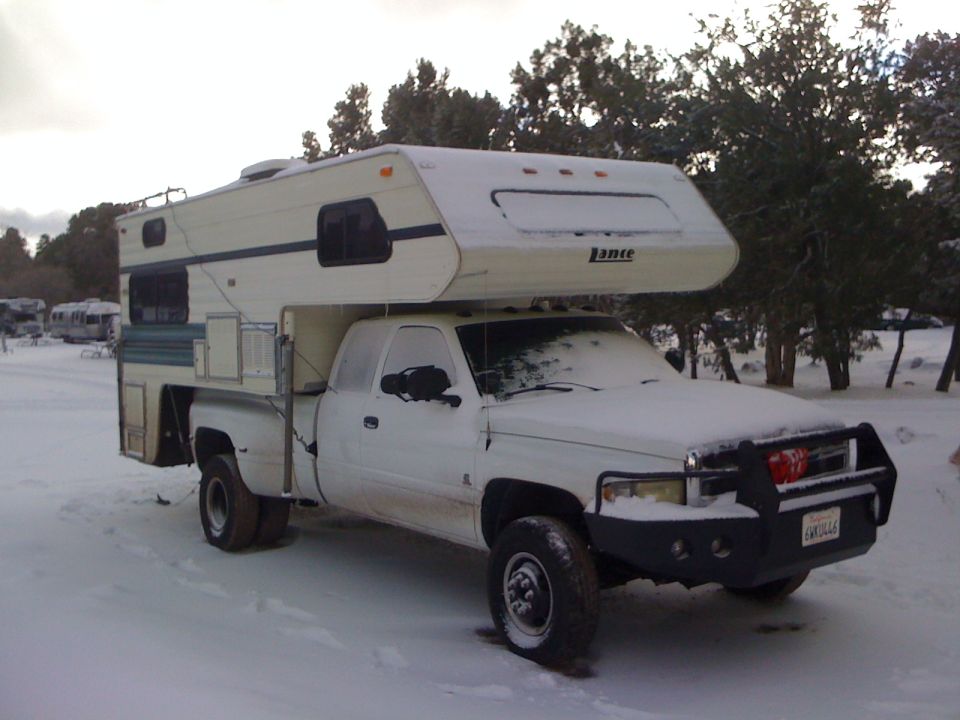 White 1997 Dodge 3500 pickup truck with a camper shell in the snow