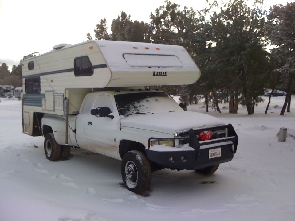 1997 Dodge 3500 pickup truck with a Lance camper shell, parked in the snow