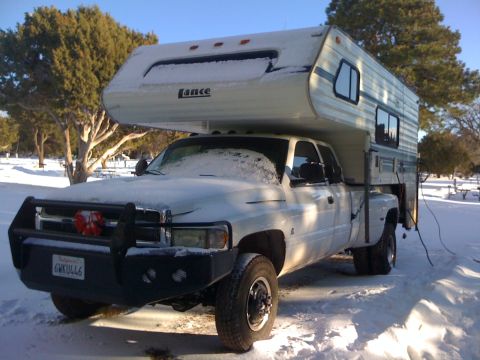1997 Dodge 3500 - A white Dodge Ram truck, equipped with a camper and a brush guard, sits in a snowy landscape.