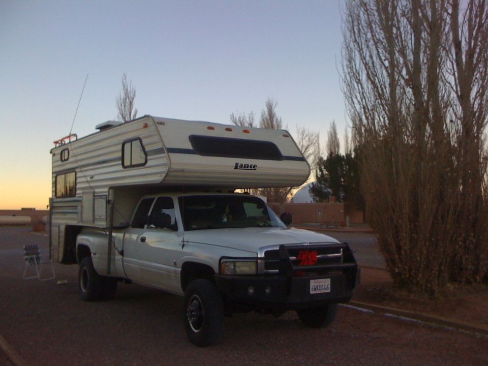 White 1997 Dodge 3500 pickup truck with camper shell, front bull bar decorated with red bows