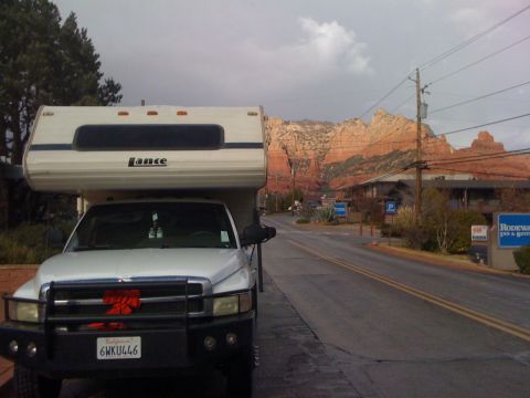 1997 Dodge 3500 - A Dodge Ram pickup truck with a Lance camper shell is parked on a road with red rock mountains in the distance.