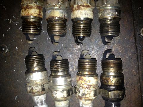 1989 Ford Bronco - A collection of eight used spark plugs, showing varying degrees of wear and fouling from engine use.