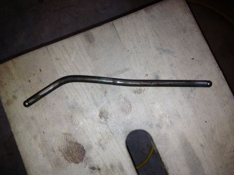 1989 Ford Bronco - A metal rod with a bent shape and rounded ends rests on a wooden surface.