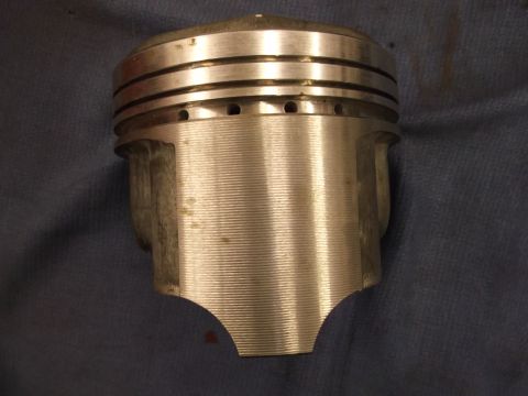 1971 Ford Ranchero - A single engine piston is shown against a dark fabric background, with visible machining marks and ring grooves.