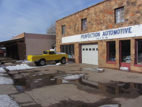 1964 Ford Ranchero - A yellow pickup truck is parked in front of an automotive shop with a sign that reads 'PERFECTION AUTOMOTIVE'.