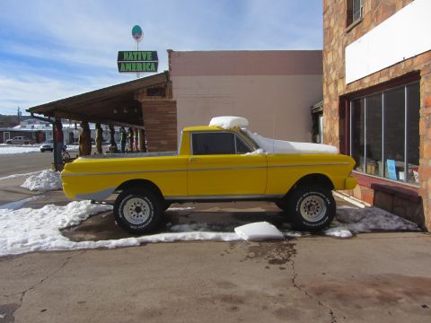 1964 Ford Ranchero - A yellow 1964 Ford Ranchero sits covered in snow outside a building with a 'Native America' sign.