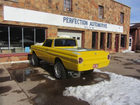 1964 Ford Ranchero - A bright yellow 1964 Ford Ranchero is parked outside Perfection Automotive on a snowy day.