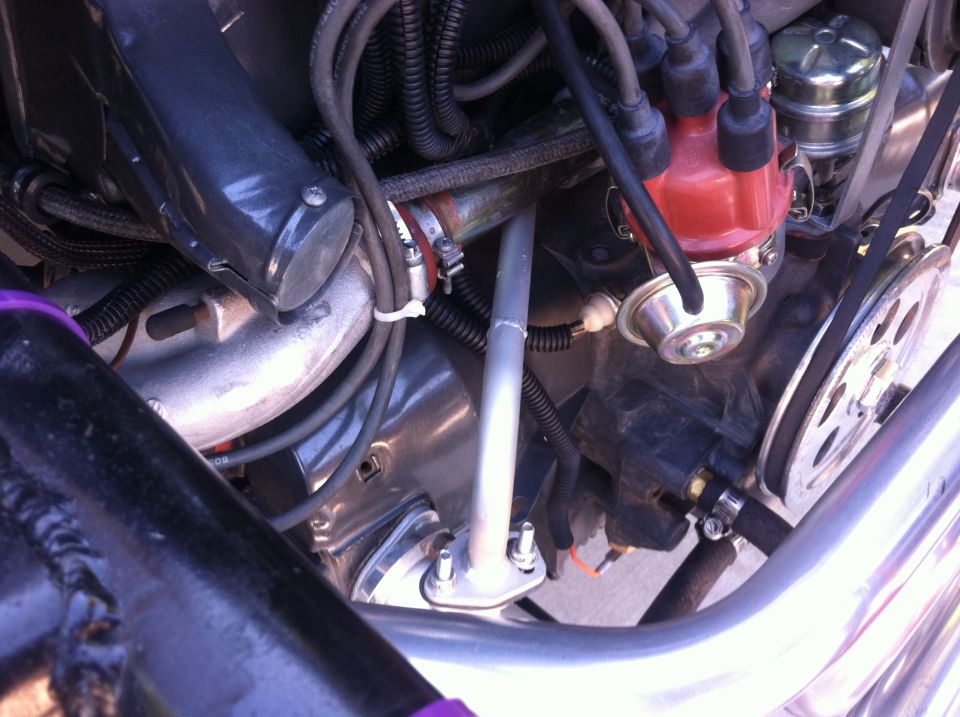 Engine bay with distributor, hoses, and fan belt visible. Some purple accents on frame