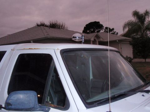 1995 Ford Bronco - A white SUV is parked in front of a house, a roof-mounted spotlight and an antenna.