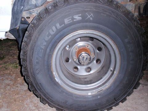 1995 Ford Bronco - Close-up of a Hercules Trail-digger tire and steel wheel assembly with a manual locking hub.