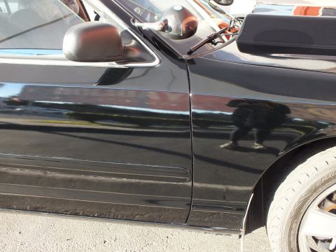2003 Ford Crown Victoria - Side detail of a black car's fender and door with a reflection on the glossy paint.